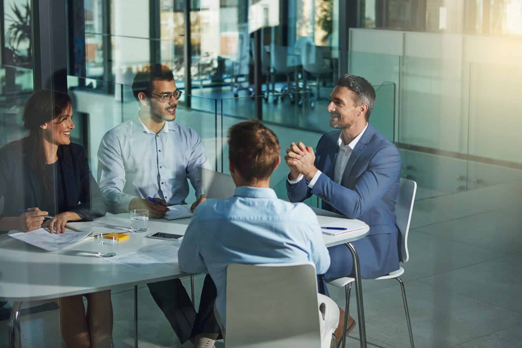 Four business people are chatting at a table in the office.