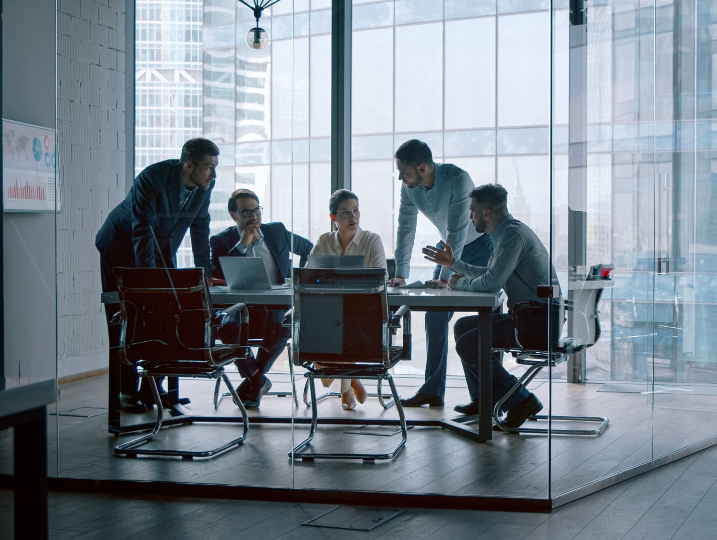 Ein Team von Businessleuten sitzen in einem Büro am Tisch und disktuieren.